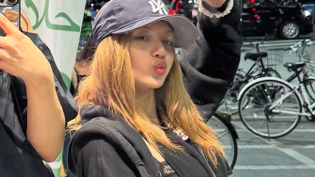 BLACKPINK's Lisa shares unique street fashion photos from Japan, featuring layered outfits and playful poses, captivating fans' curiosity.